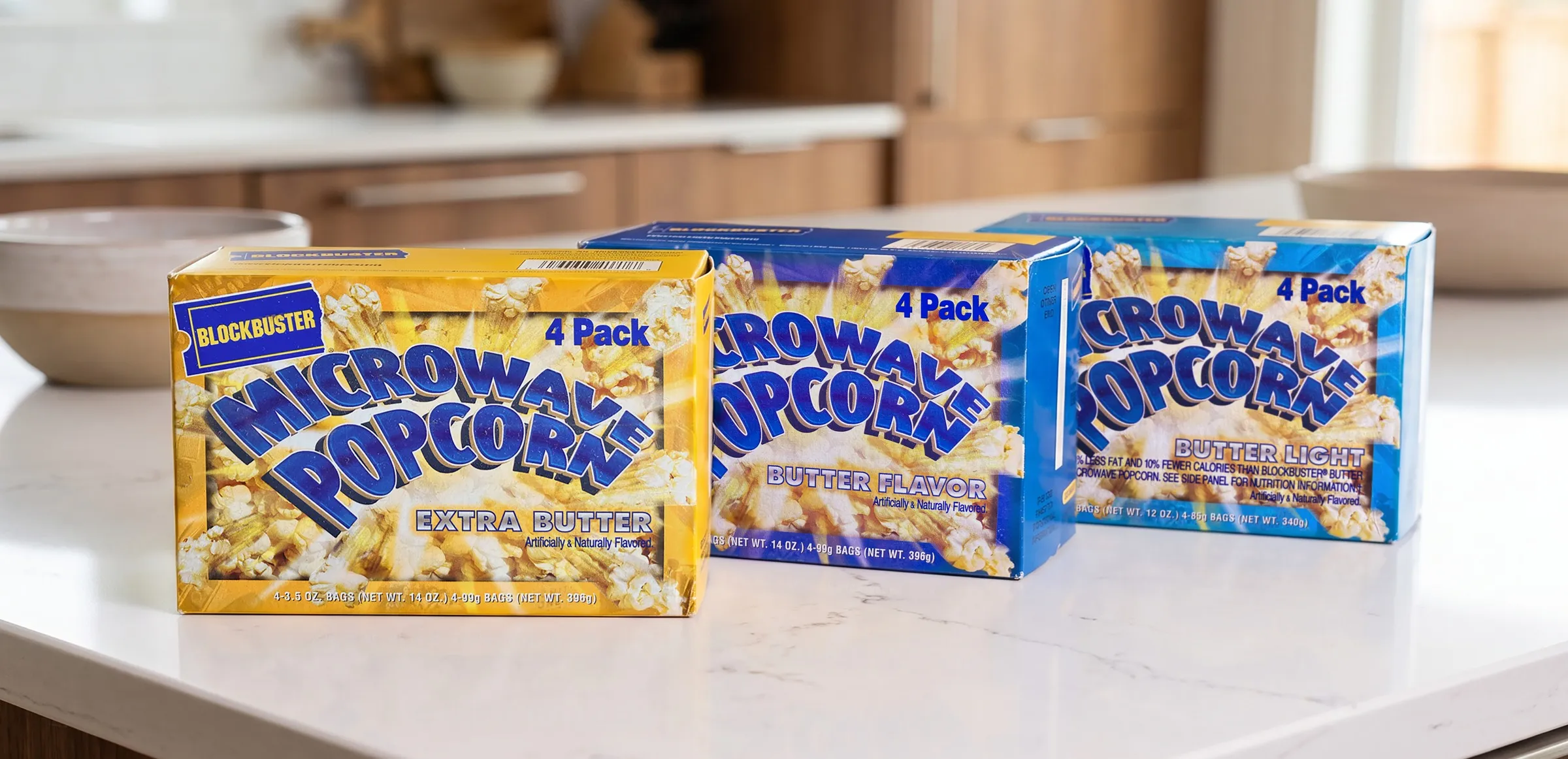 Three Blockbuster four-pack cartons on a kitchen counter in Extra Butter, Butter Flavor, and Butter Light.