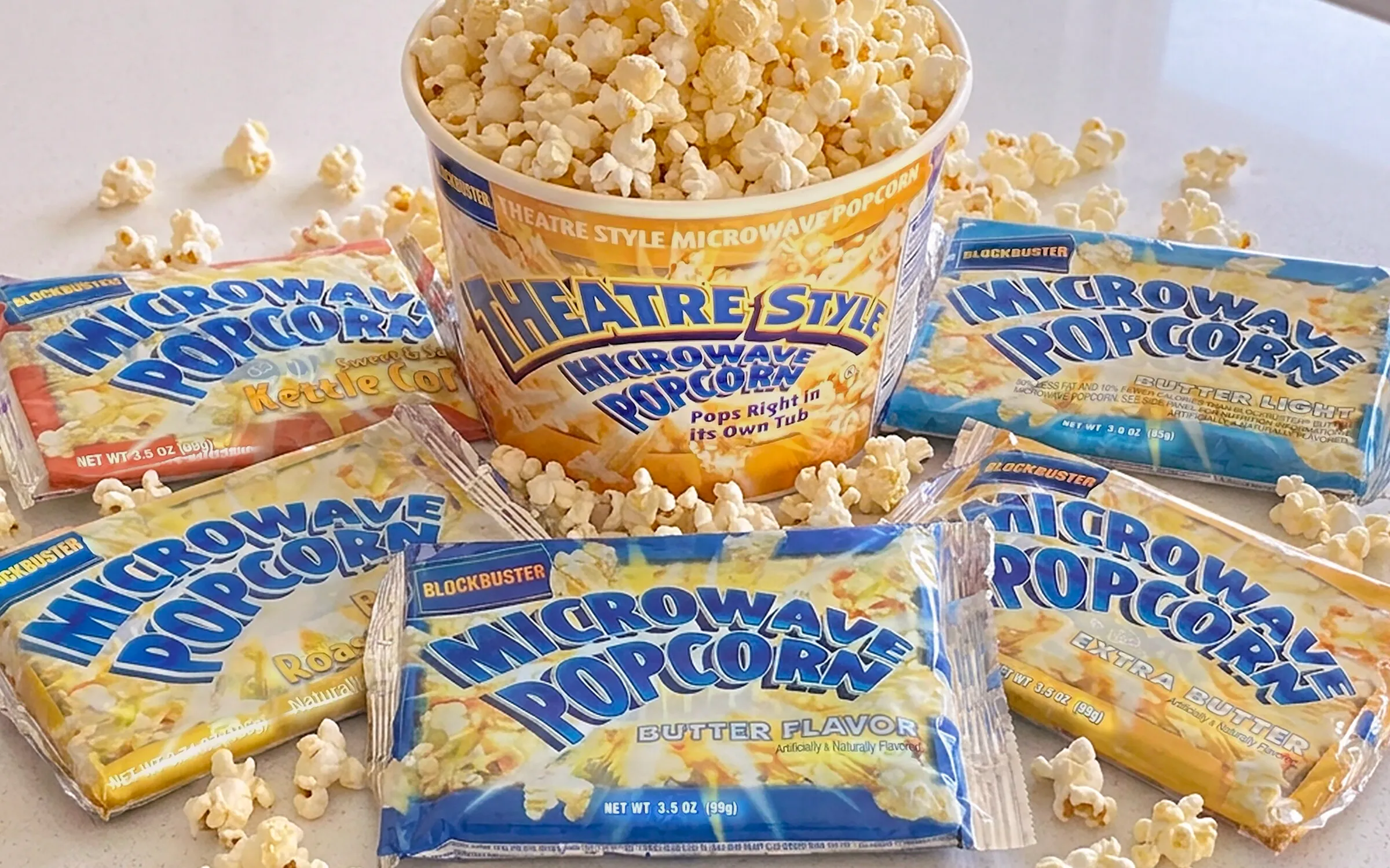 Blockbuster microwave popcorn line — a Theatre Style tub surrounded by flavor packets and scattered popcorn.