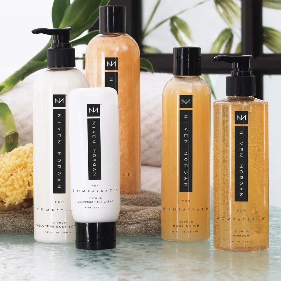The citrus group: body lotion, hand crème, body wash, body scrub, and hand soap in amber and white on a glass shelf.