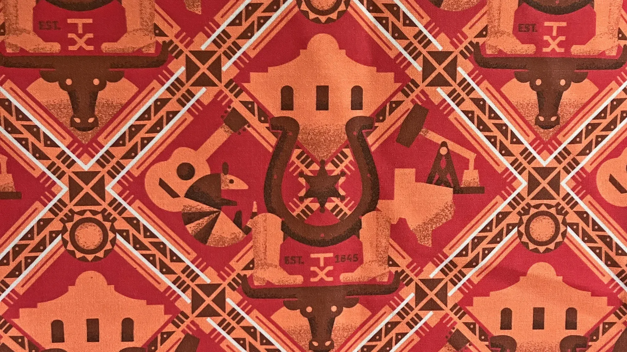 The finished Texas pattern printed on cloth, a diagonal lattice of longhorns, missions, guitars, and horseshoes in red, orange, and brown.